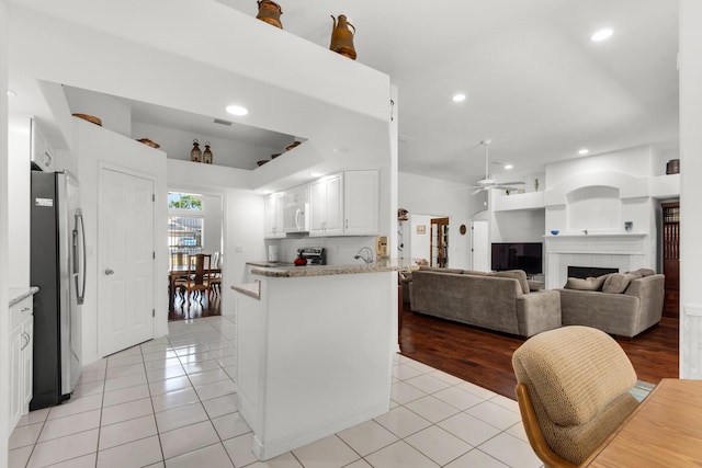 kitchen with stainless steel appliances, a ceiling fan, light tile patterned flooring, and a fireplace