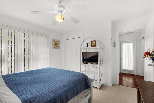 carpeted bedroom with a closet, baseboards, visible vents, and a ceiling fan