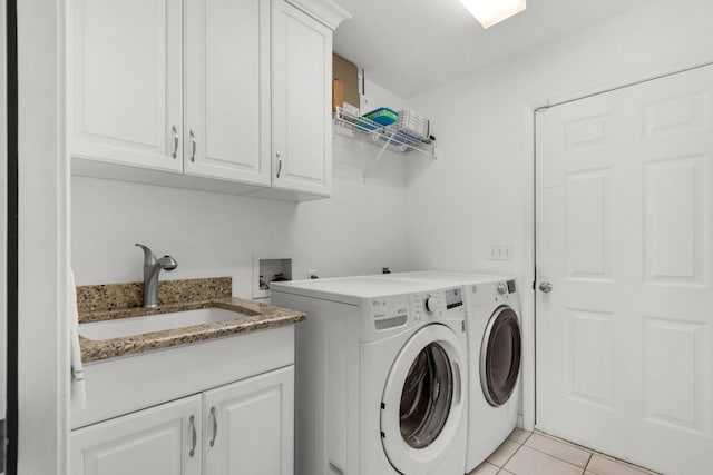 clothes washing area featuring light tile patterned floors, washing machine and dryer, cabinet space, and a sink