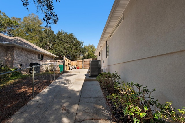 view of side of property featuring a patio, cooling unit, fence, and brick siding