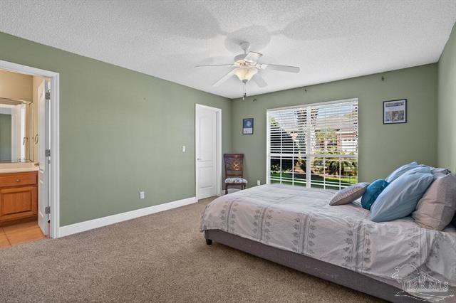 1607 Woodlawn Way, Gulf Breeze, FL 32563 - bedroom featuring light colored carpet, a textured ceiling, ensuite bathroom, and ceiling fan