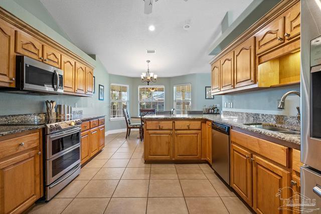 1607 Woodlawn Way, Gulf Breeze, FL 32563 - kitchen with appliances with stainless steel finishes, light tile patterned flooring, brown cabinetry, a chandelier, and a peninsula