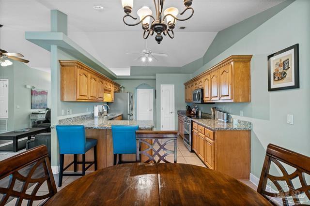 1607 Woodlawn Way, Gulf Breeze, FL 32563 - kitchen with ceiling fan, appliances with stainless steel finishes, a peninsula, a breakfast bar, and vaulted ceiling