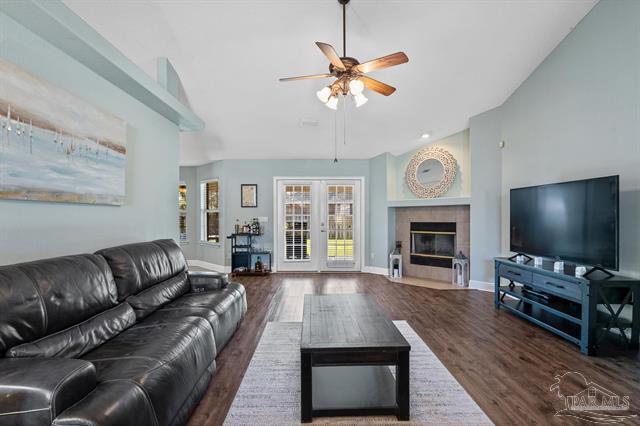 1607 Woodlawn Way, Gulf Breeze, FL 32563 - living room with a ceiling fan, vaulted ceiling, wood finished floors, and a tiled fireplace