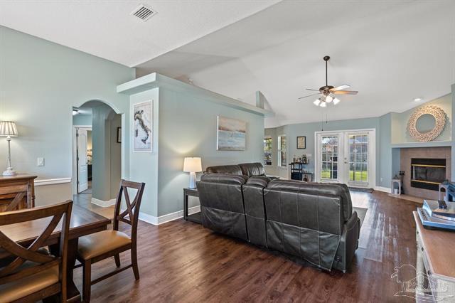 1607 Woodlawn Way, Gulf Breeze, FL 32563 - living room featuring ceiling fan, vaulted ceiling, dark wood finished floors, arched walkways, and a fireplace with flush hearth