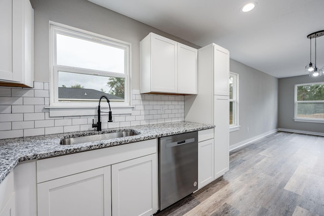 kitchen featuring light wood-style flooring, a sink, white cabinets, dishwasher, and tasteful backsplash