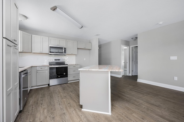 kitchen featuring decorative backsplash, appliances with stainless steel finishes, a center island, and wood finished floors