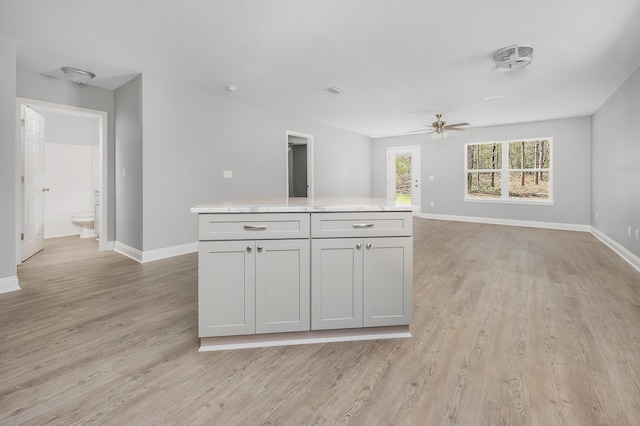 kitchen featuring baseboards, light wood-style floors, open floor plan, and a ceiling fan