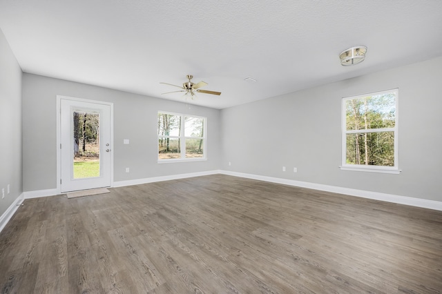 spare room featuring ceiling fan, a textured ceiling, baseboards, and wood finished floors