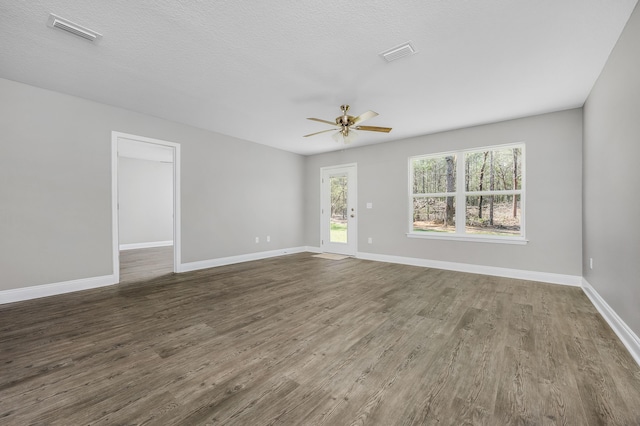 unfurnished room featuring dark wood finished floors, visible vents, and baseboards