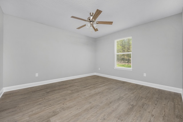 spare room featuring a textured ceiling, wood finished floors, baseboards, and ceiling fan