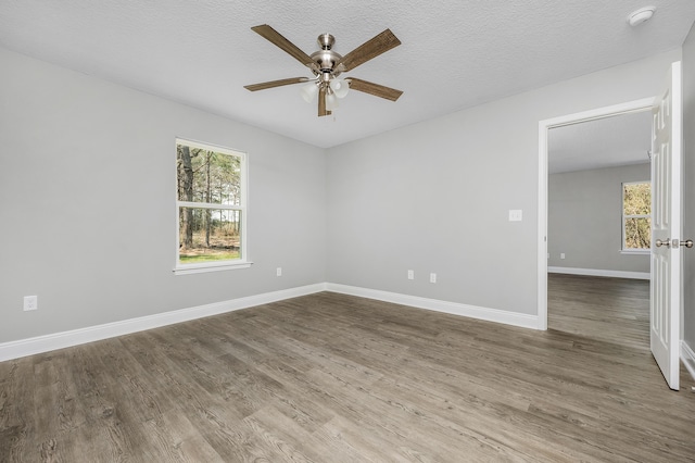 spare room featuring wood finished floors, baseboards, and a textured ceiling