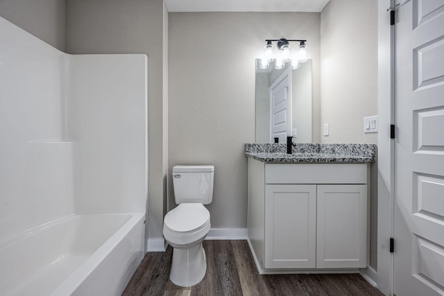 full bathroom with toilet, shower / washtub combination, wood finished floors, baseboards, and vanity