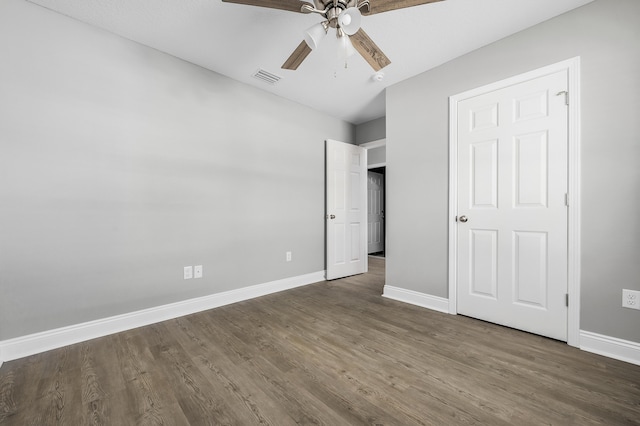 unfurnished bedroom featuring a ceiling fan, dark wood-style floors, visible vents, and baseboards