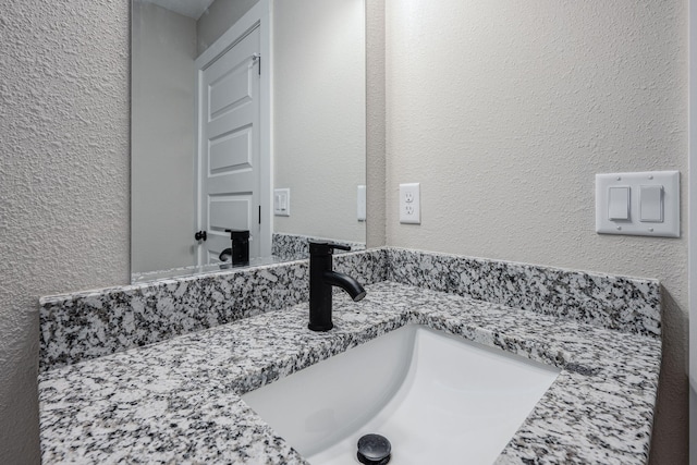 bathroom with vanity and a textured wall