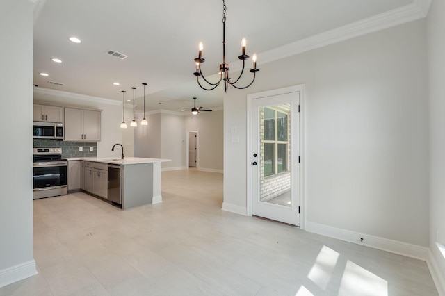 kitchen featuring open floor plan, ornamental molding, appliances with stainless steel finishes, and a sink