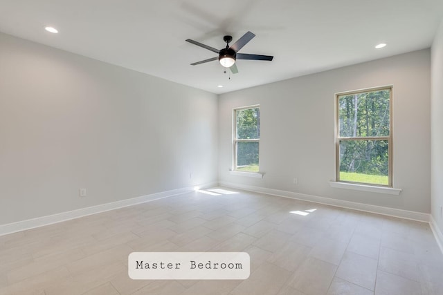 spare room with baseboards, a healthy amount of sunlight, and a ceiling fan