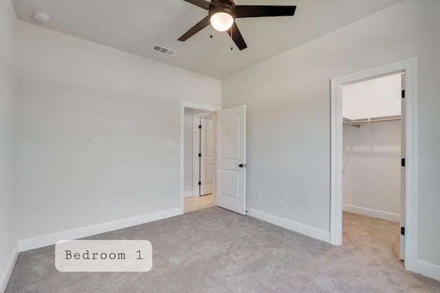 unfurnished bedroom featuring a spacious closet, visible vents, baseboards, carpet flooring, and a closet