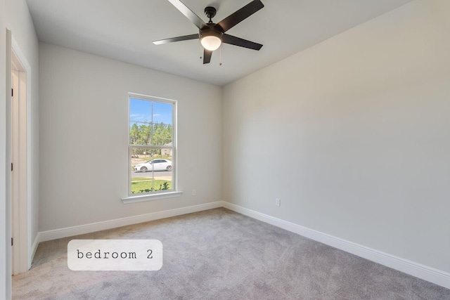 unfurnished room with a ceiling fan, baseboards, and light carpet