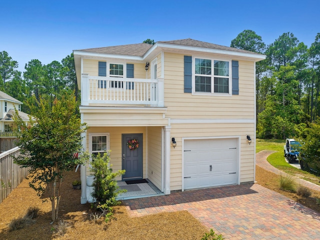 view of front of house featuring a garage, a balcony, and fence