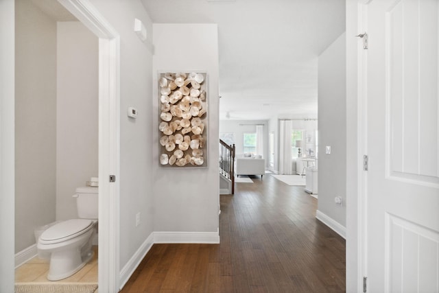 corridor featuring stairway, baseboards, and dark wood-style flooring