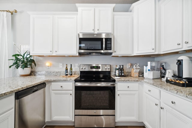 kitchen featuring white cabinetry, light stone counters, and appliances with stainless steel finishes