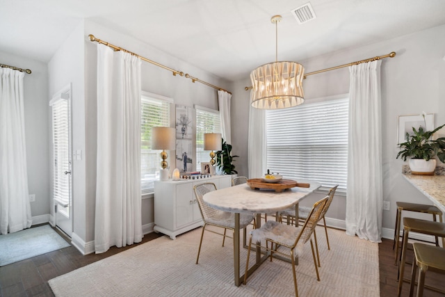 dining area with visible vents, baseboards, an inviting chandelier, and wood finished floors