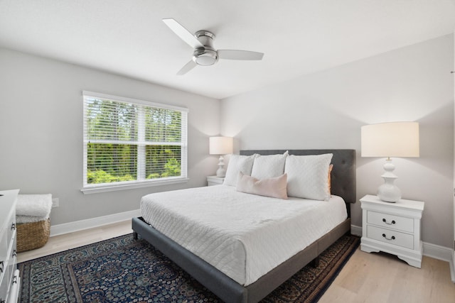 bedroom featuring light wood finished floors, a ceiling fan, and baseboards