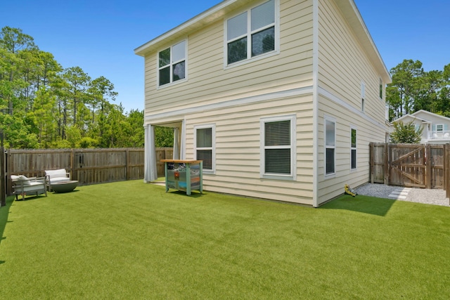 back of property with a lawn, a fenced backyard, and a gate