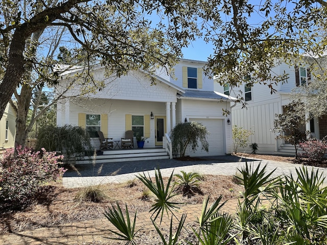 view of front of home with an attached garage, a porch, and driveway