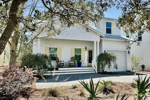 view of front facade featuring metal roof, driveway, a porch, and an attached garage