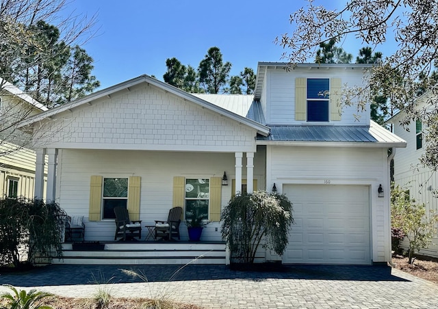 view of front of home featuring a porch, decorative driveway, a garage, and metal roof