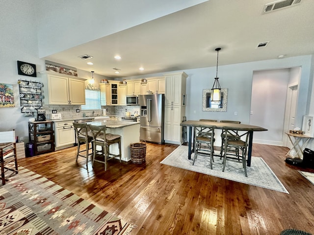 kitchen with stainless steel appliances, visible vents, dark wood-style flooring, and a center island