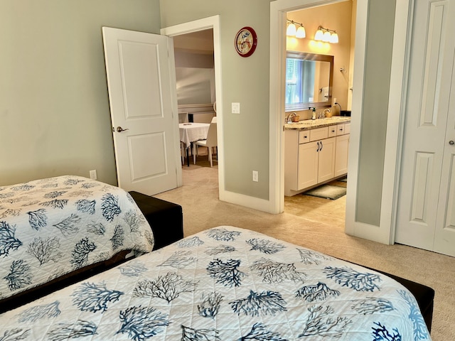 bedroom with light carpet, ensuite bathroom, baseboards, and a sink