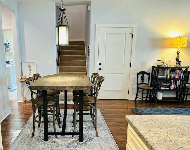 dining area featuring stairway, washer / clothes dryer, and dark wood-style floors