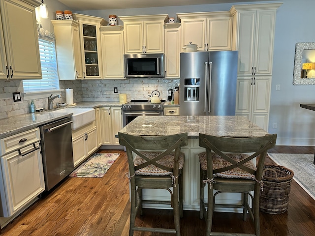 kitchen featuring stainless steel appliances, tasteful backsplash, cream cabinets, and dark wood-style flooring