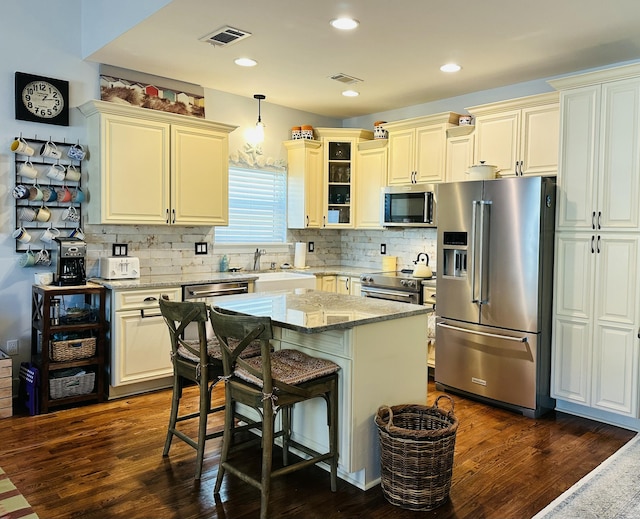 kitchen featuring visible vents, light stone countertops, stainless steel appliances, and a sink