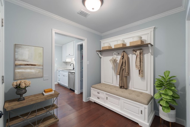 mudroom featuring visible vents, crown molding, baseboards, dark wood-type flooring, and a sink