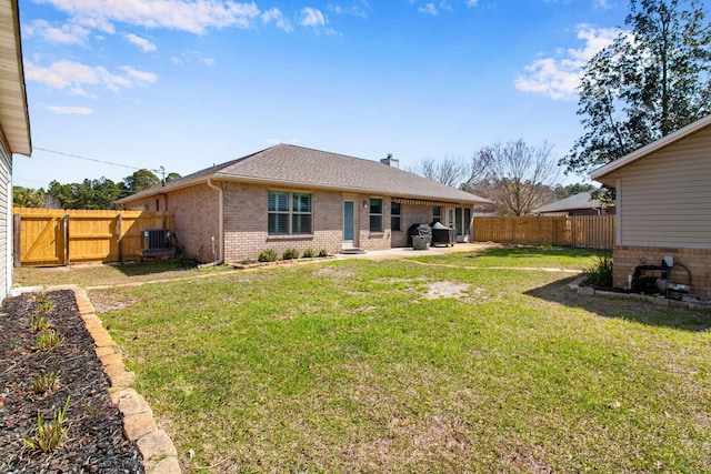 rear view of property with central air condition unit, brick siding, a fenced backyard, and a lawn