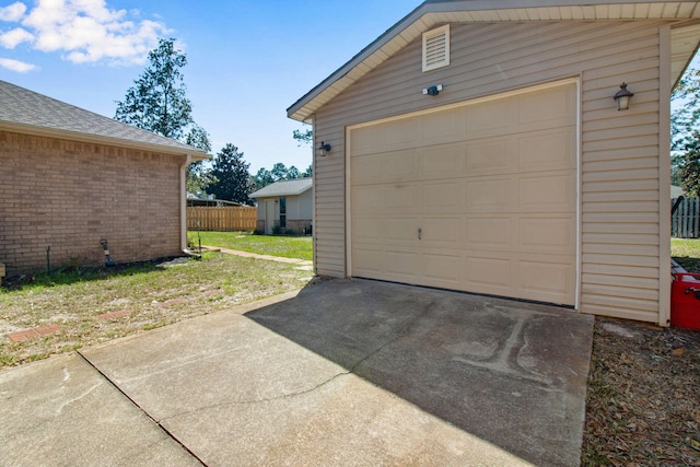 garage featuring driveway and fence