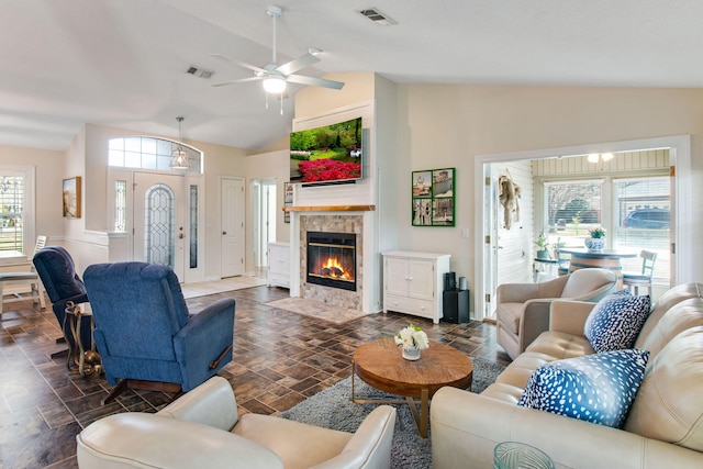 living room featuring visible vents, a tile fireplace, a ceiling fan, and vaulted ceiling