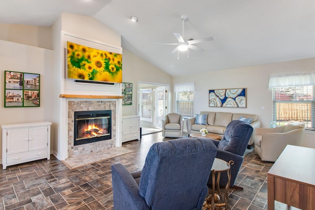 living area featuring ceiling fan, stone finish floor, high vaulted ceiling, and a tile fireplace