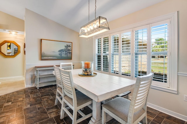 dining area with visible vents, stone finish flooring, baseboards, and vaulted ceiling