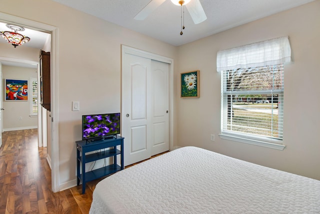 bedroom featuring a closet, a ceiling fan, baseboards, and wood finished floors