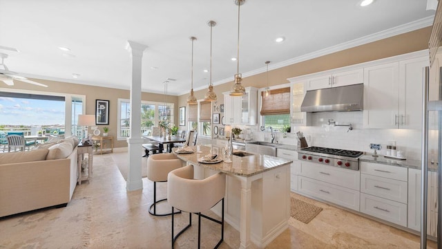 kitchen with ornamental molding, a sink, stainless steel gas stovetop, white cabinets, and under cabinet range hood