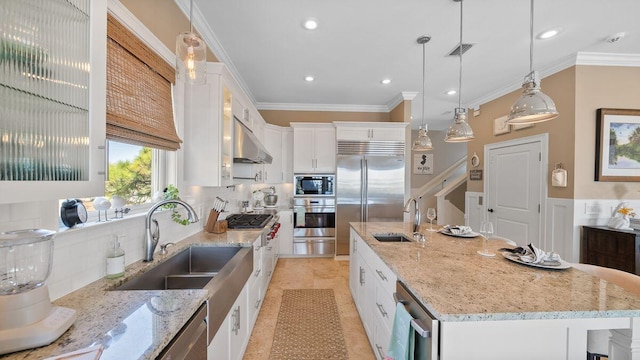 kitchen with visible vents, a large island with sink, a sink, built in appliances, and white cabinetry