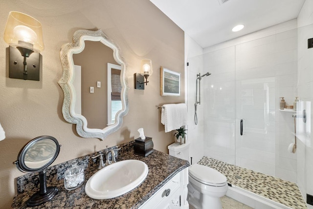 bathroom featuring a stall shower, toilet, and vanity