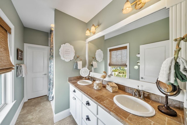 bathroom with a sink, baseboards, and double vanity