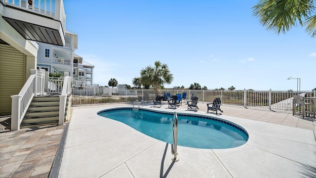 community pool featuring stairway, fence, and a patio area