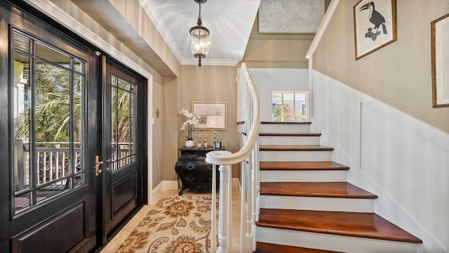 entrance foyer featuring a chandelier, stairway, french doors, and crown molding